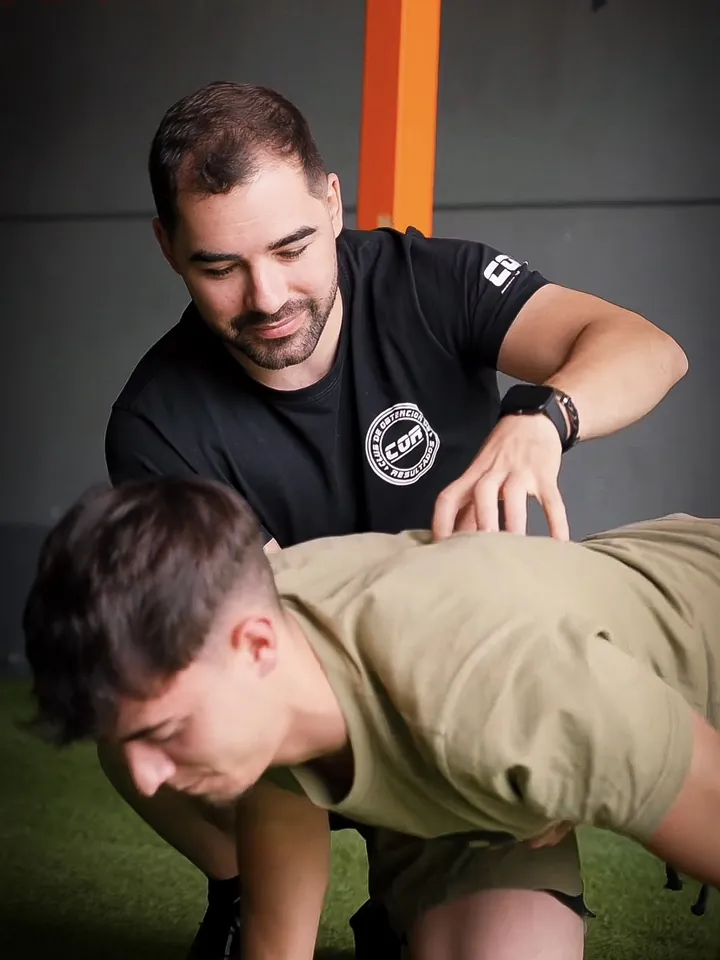 Entrenador personal corrigiendo la técnica de un alumno en COR Club, La Pobla de Vallbona